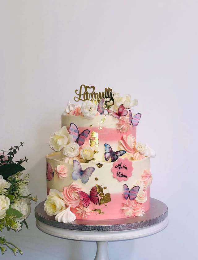 Tort aniversar roz decorat cu fluturi și flori
